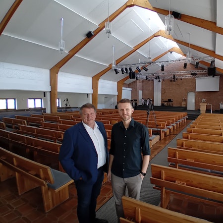 Zwei Männer in einer großen leeren Kirche.