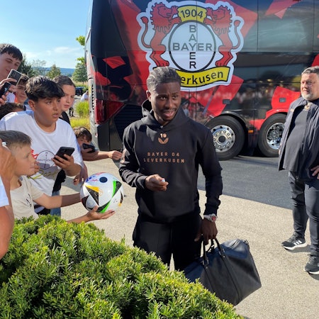 Leverkusens Angreifer Nathan Tella schreibt nach der Ankunft in Donaueschingen Autogramme.