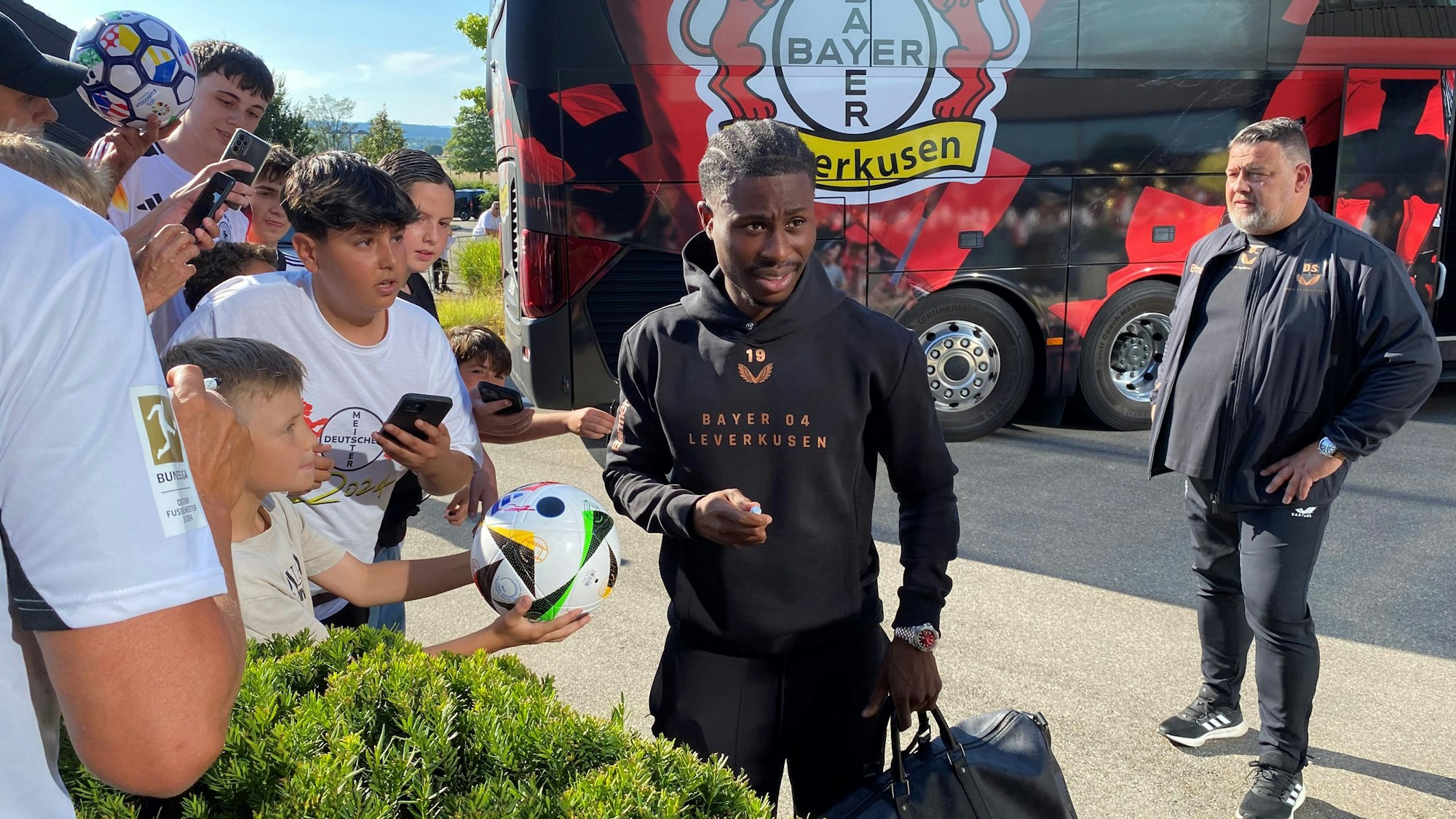 Leverkusens Angreifer Nathan Tella schreibt nach der Ankunft in Donaueschingen Autogramme.