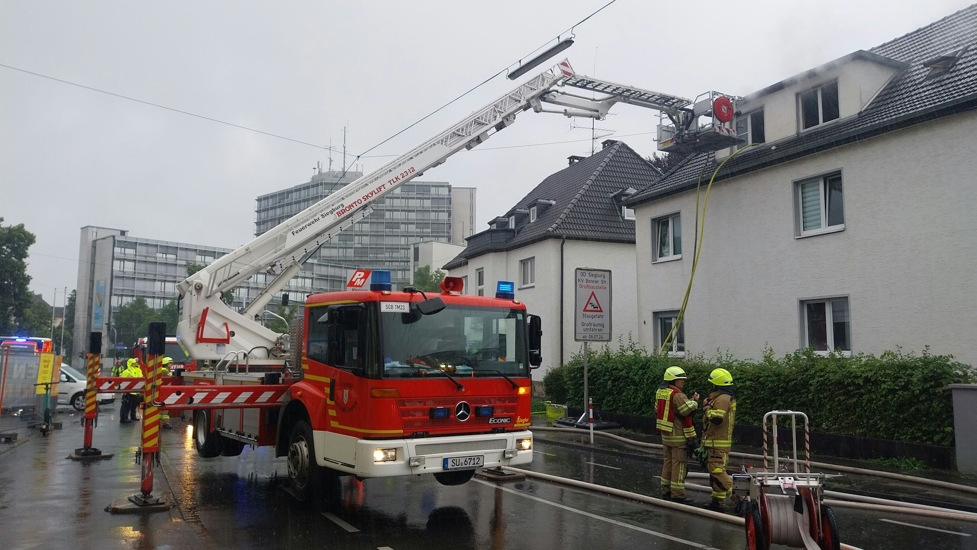 Ein Teleskopmastfahrzeug der Feuerwehr im Einsatz vor einem Haus.