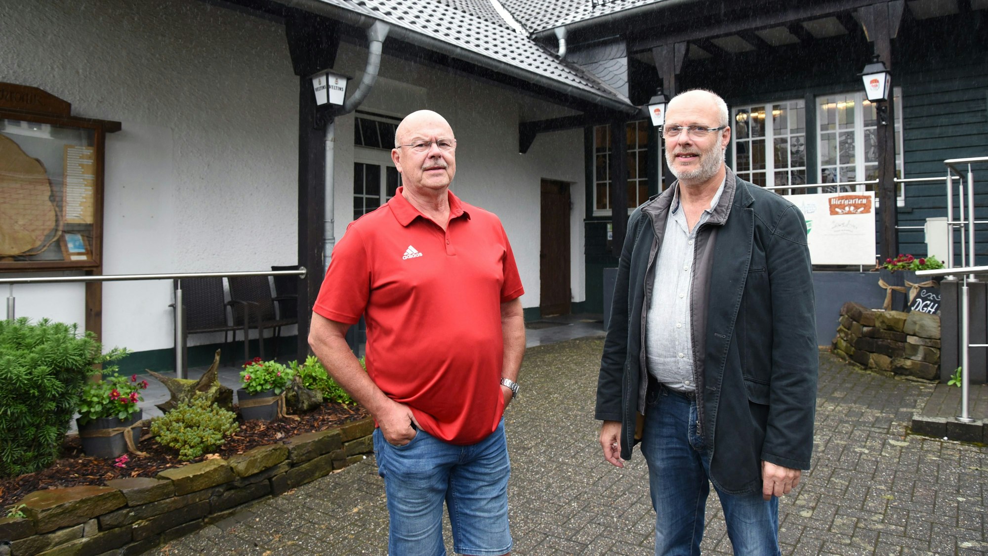 Zwei Männer stehen vor dem Eingang einer Gaststätte.