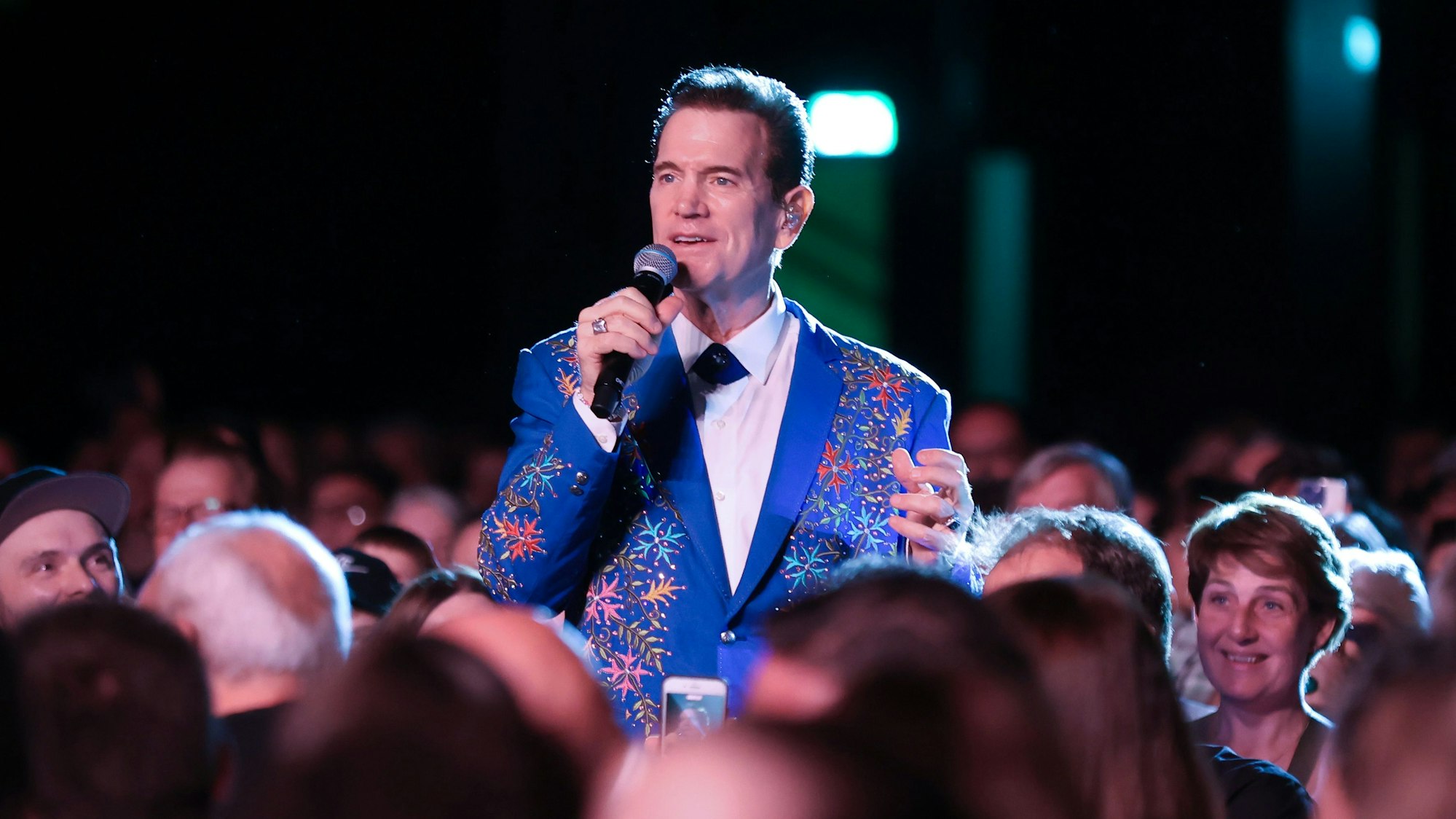 Chris Isaak singt mitten im Publikum. Er trägt einen mit Stickereien verzierten blauen Anzug. 28.07.2024
Köln:
Konzert von Chris Isaak
im Palladium
Foto: Martina Goyert