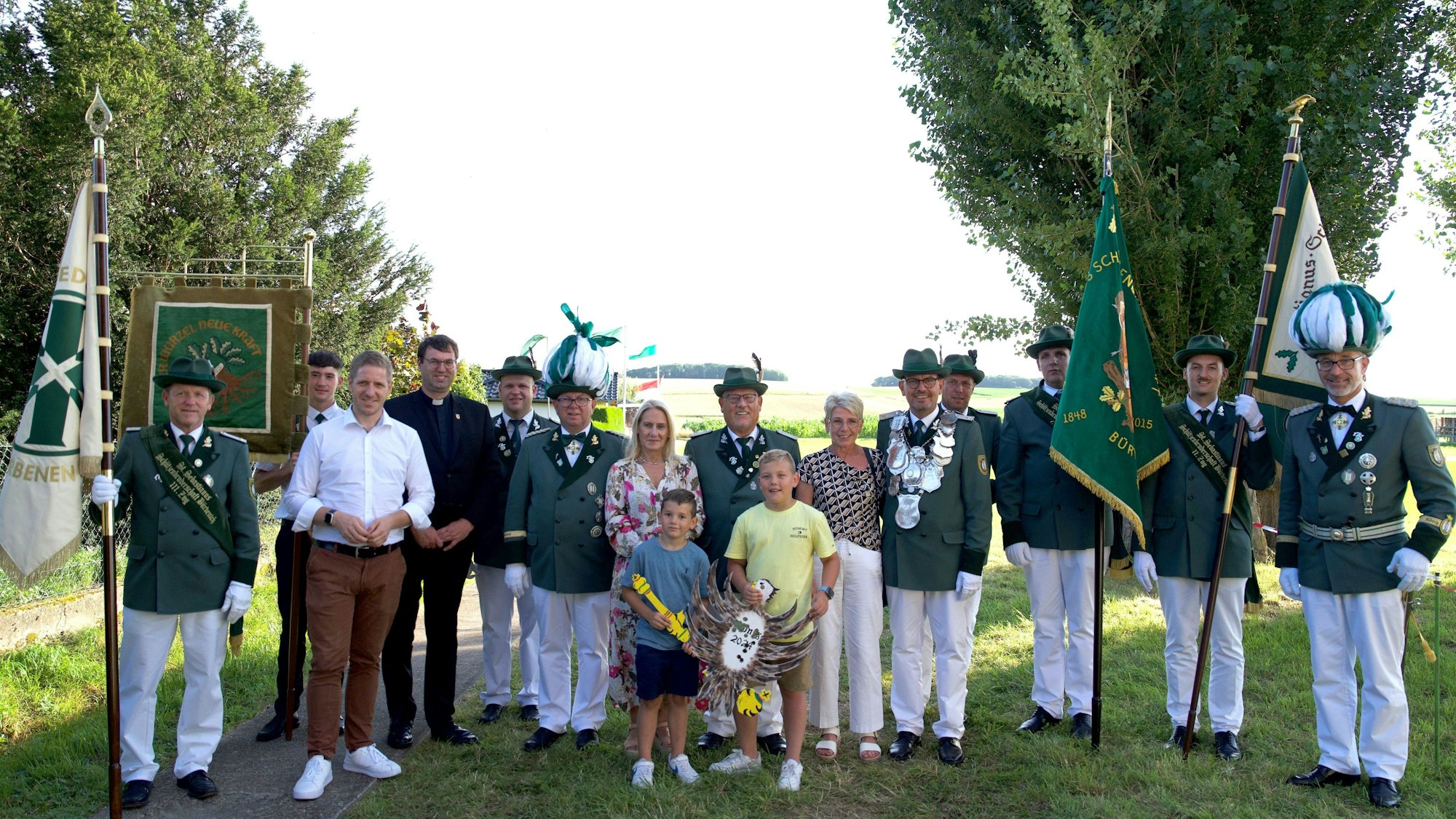 Der neue König Jörg Körtgen steht beim Erinnerungsfoto hinter seinen Enkelkindern, die den Holzvogel tragen. Mit dabei sind Landrat Markus Ramers und mehrere Schützenbrüder.