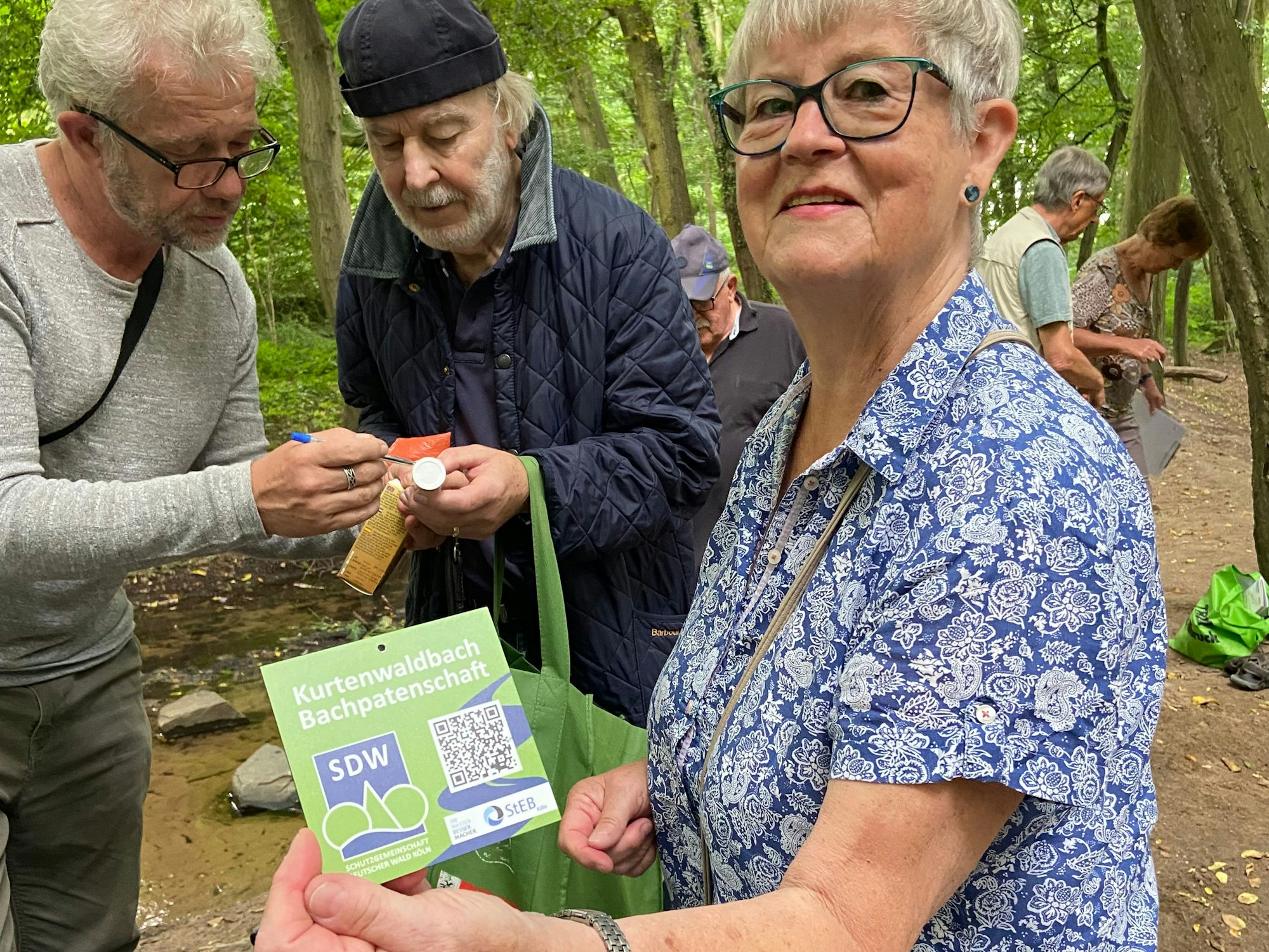 Karin Merten hält ein Schild mit einem QR-Code in der Hand.