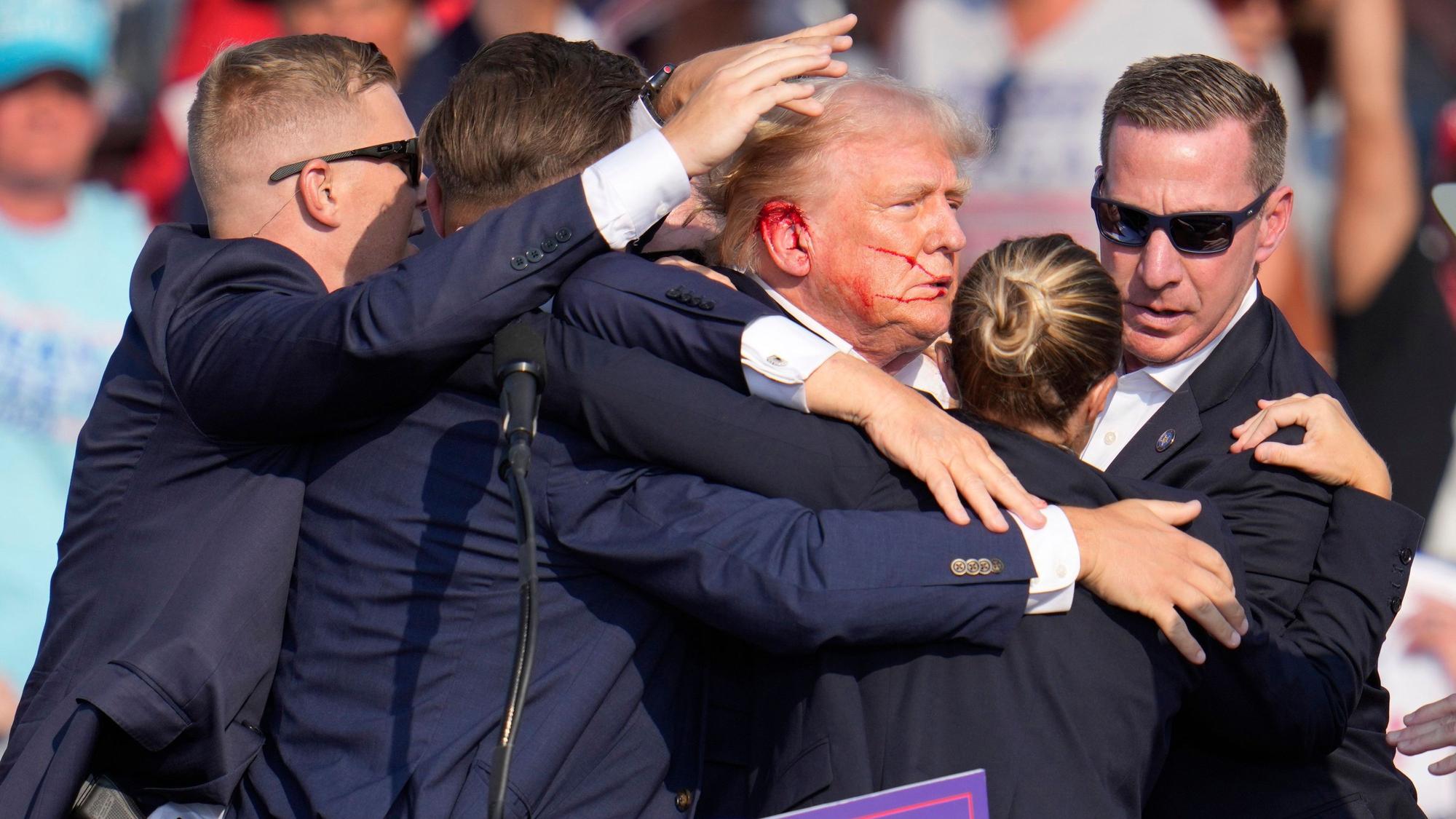 Der republikanische Präsidentschaftsbewerber und frühere US-Präsident Donald Trump wird nach den Schüssen von Agenten des US-Geheimdienstes Secret Service umringt.