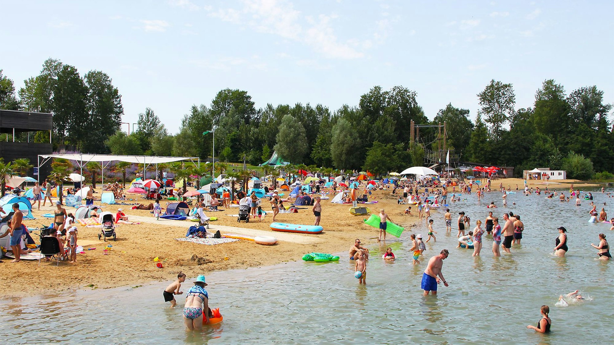 An einem schönen Sommertag sind viele Badegäste am Sandstrand des Zülpicher Wassersportsees.