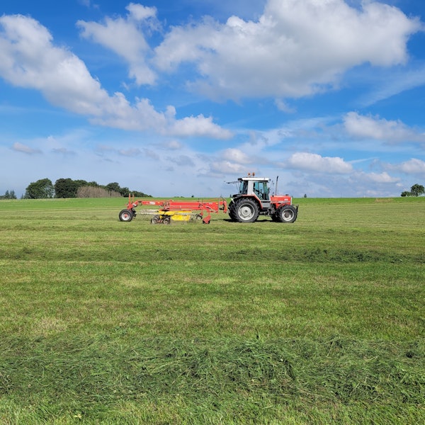 Ein Traktor fährt über eine Wiese.