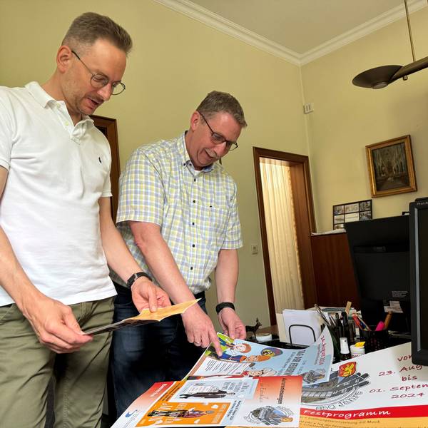Sebastian Gissinger und Guido Lemmer schauen sich die verschiedenen Plakate zur Feierwoche an.
