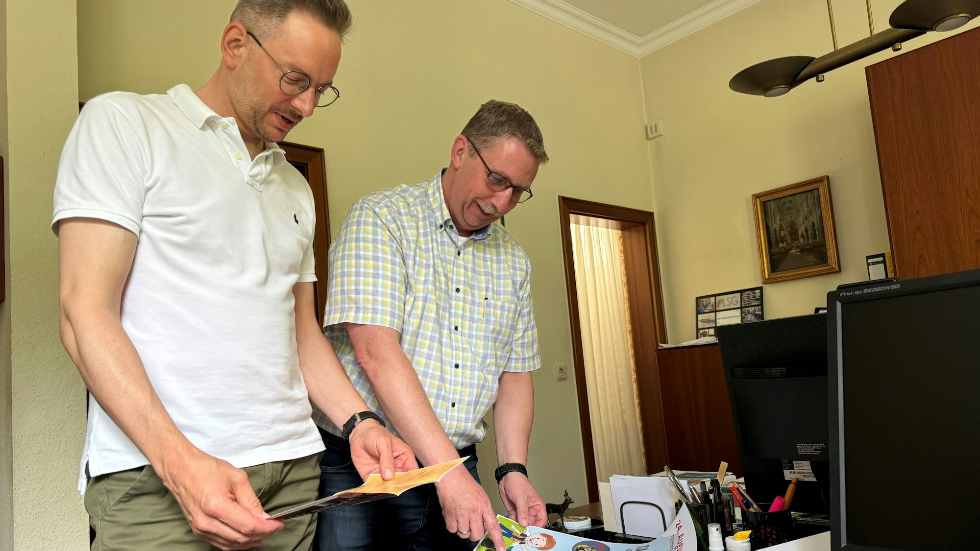 Sebastian Gissinger und Guido Lemmer schauen sich die verschiedenen Plakate zur Feierwoche an.