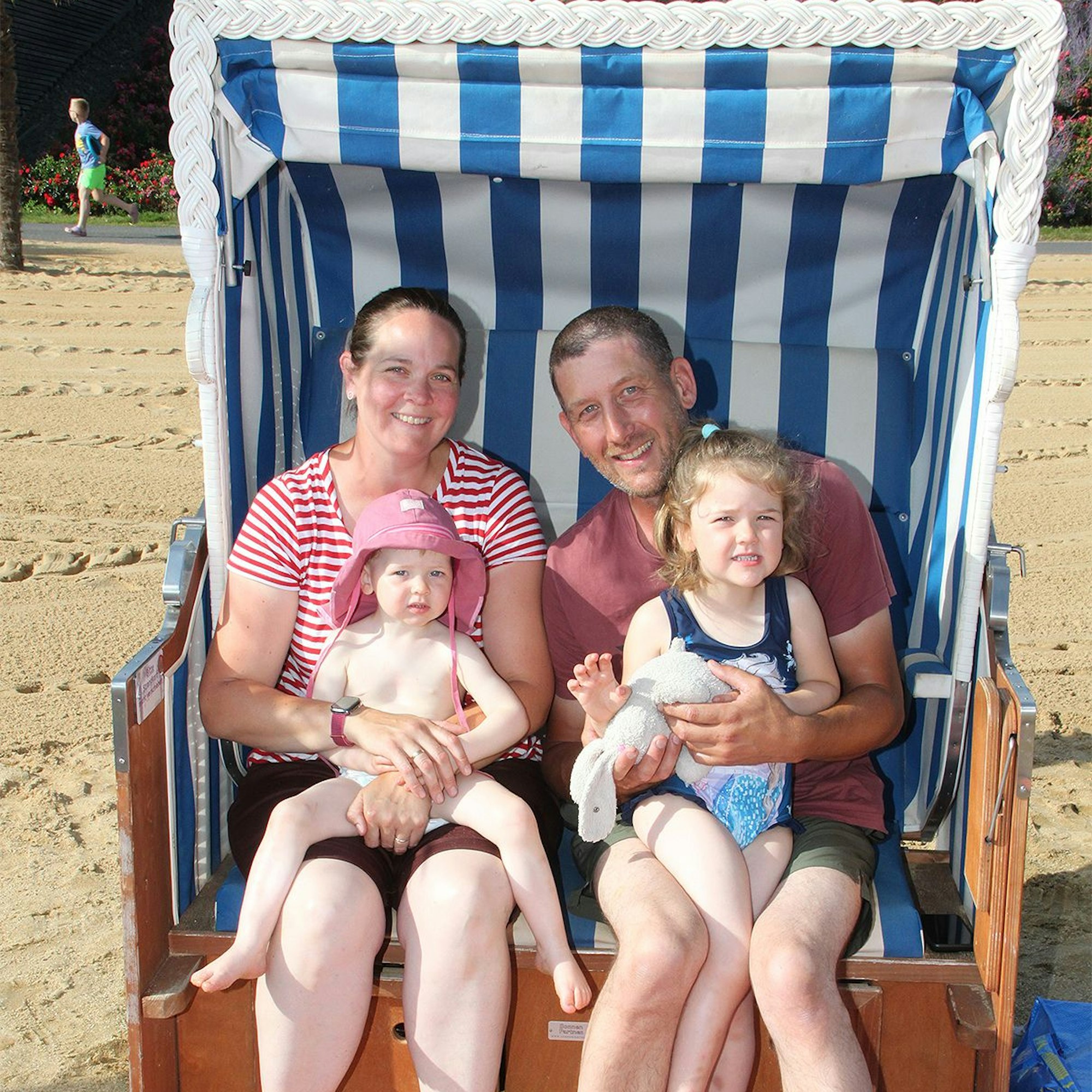 Eine Familie mit zwei Kindern sitzt in einem blau-weiß gestreiften Strandkorb am Zülpicher See.