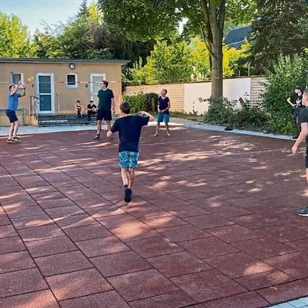 Jugendlich beim Ballspielen auf einem Schulhof.