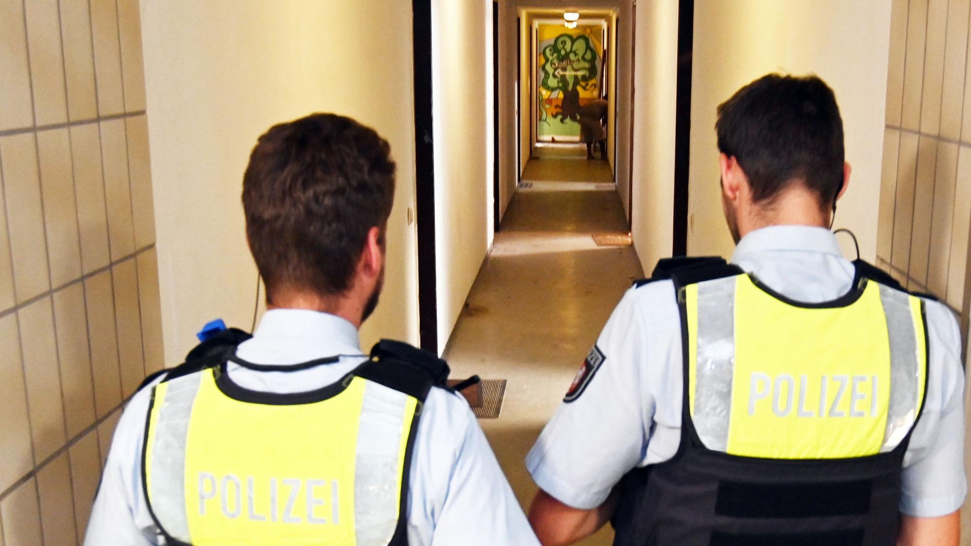 Zwei Polizisten gehen durch den Hausflur.