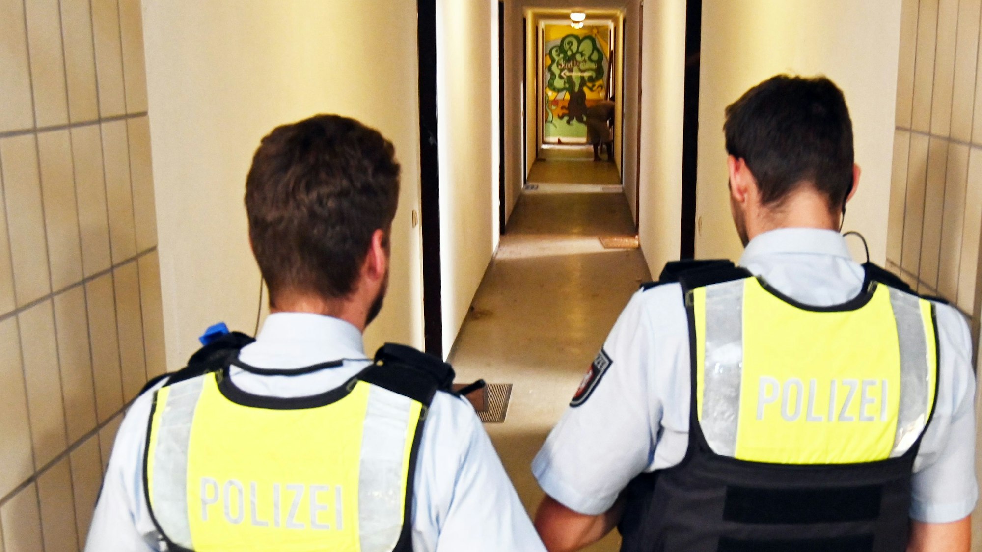 Zwei Polizisten gehen durch den Hausflur.