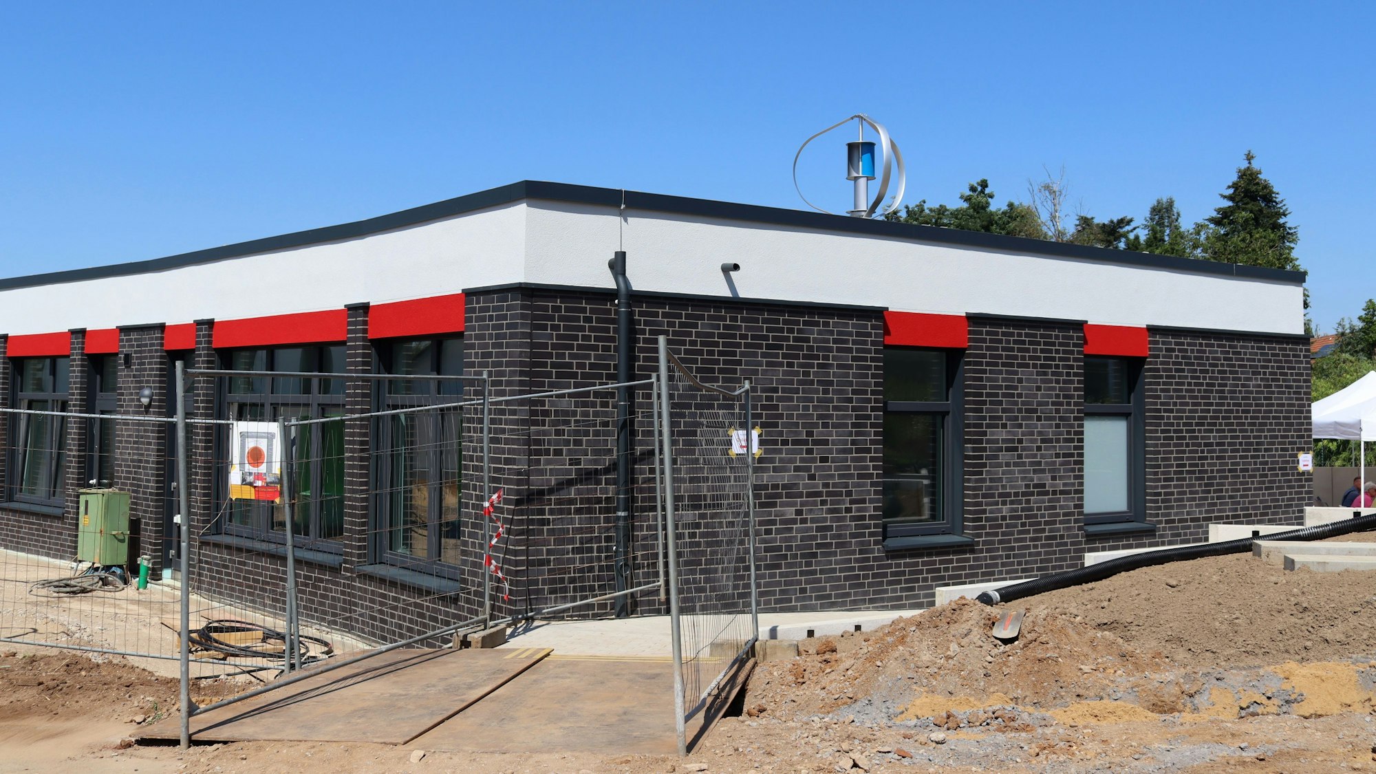 Außenaufnahme der Kindertagesstätte in Wüschheim, an der noch ein Bauzaun steht.