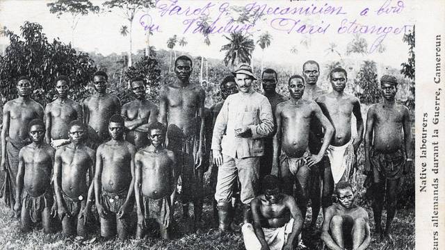 Kolonialismus als Postkartenmotiv: Ein deutscher Siedler posiert für den Fotografen mit einheimischen Arbeitern in Kamerun