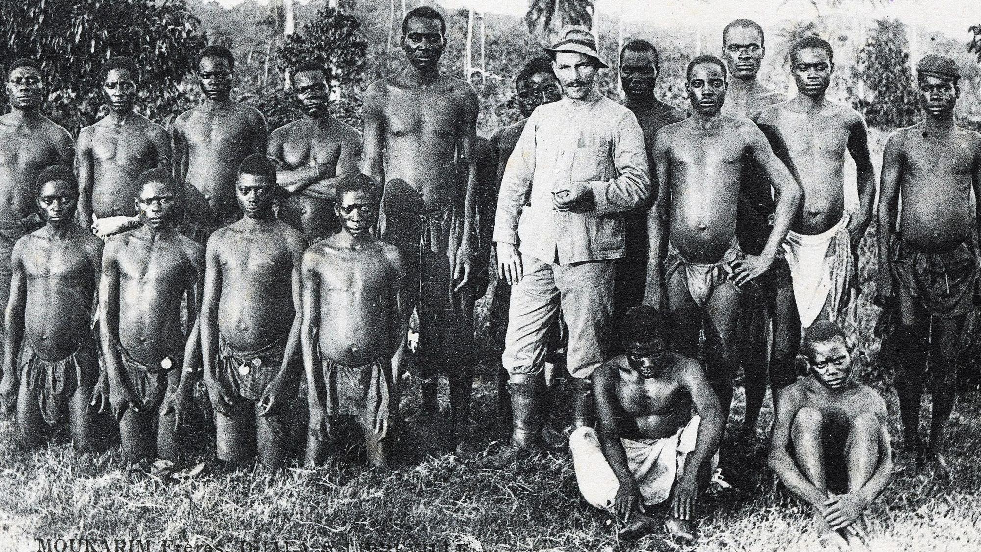 Kolonialismus als Postkartenmotiv: Ein deutscher Siedler posiert für den Fotografen mit einheimischen Arbeitern in Kamerun