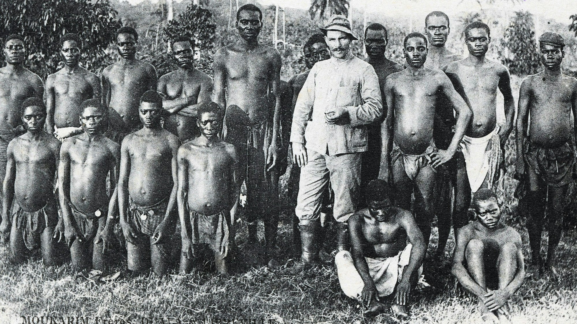 Kolonialismus als Postkartenmotiv: Ein deutscher Siedler posiert für den Fotografen mit einheimischen Arbeitern in Kamerun