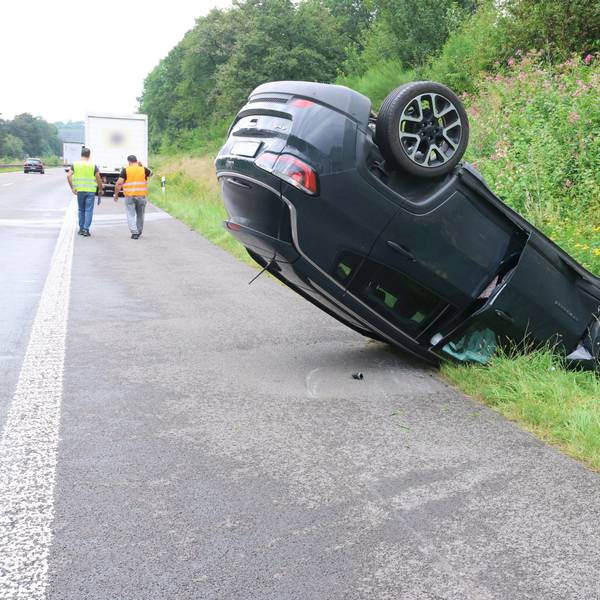 Ein Auto liegt auf einem Standstreifen einer Autobahn auf dem Dach.