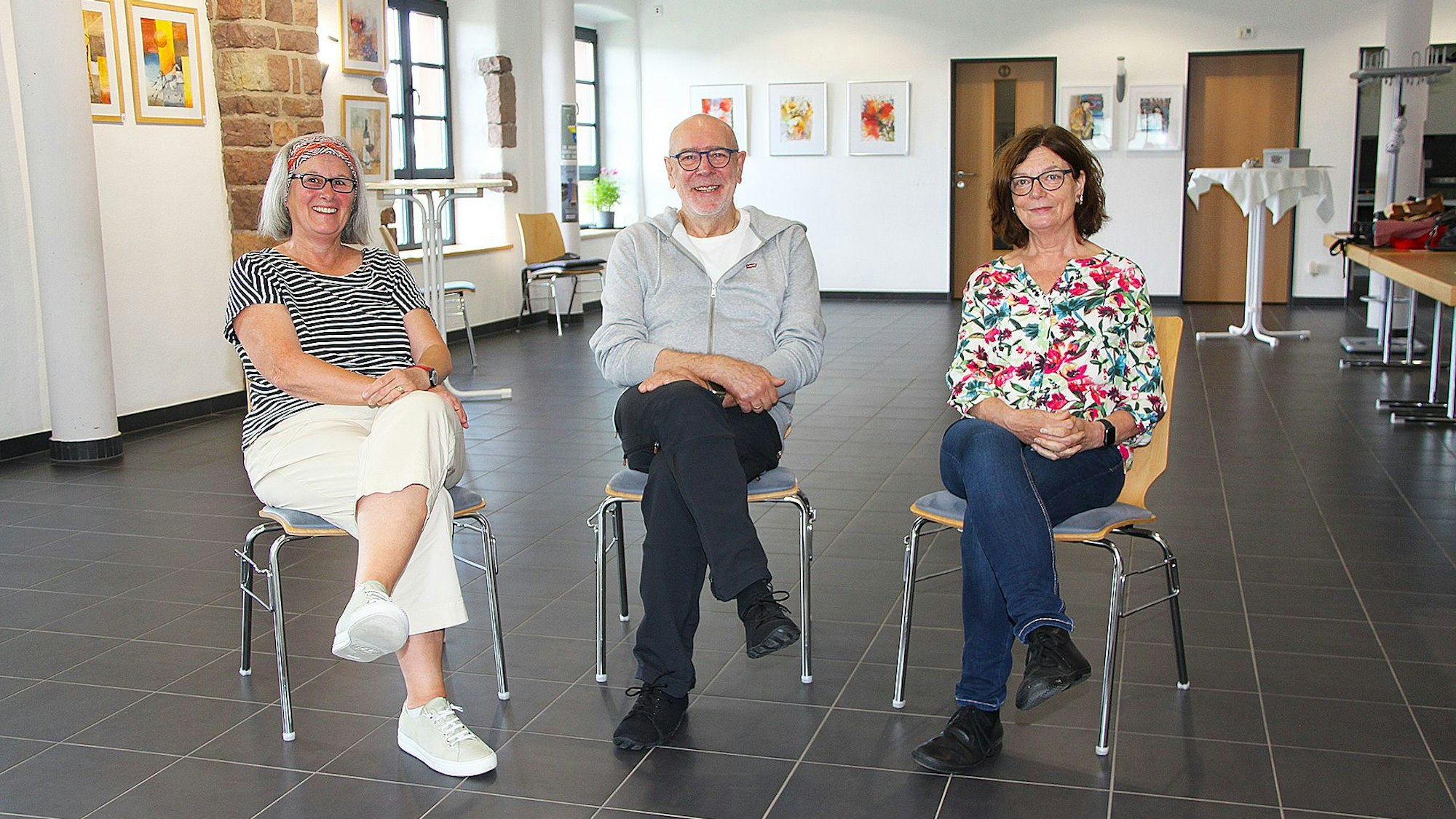 Zwei Frauen und ein Mann, Heike Plein (l.), Peter Niemann und Birgit Wagner, sitzen auf Stühlen im Haus der Kulturinitiative in Hillesheim.
