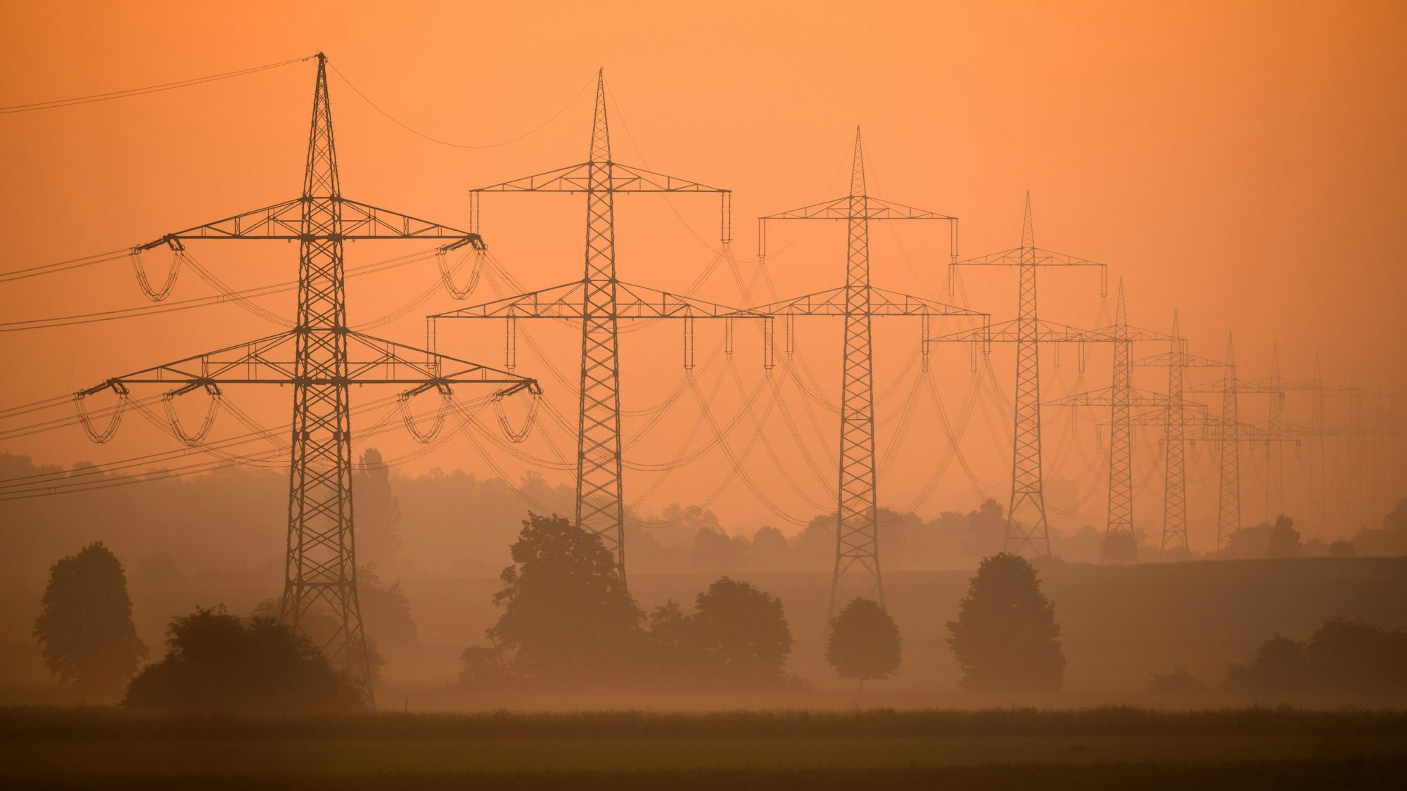 Eine Hochspannungsleitung steht im Morgenlicht.