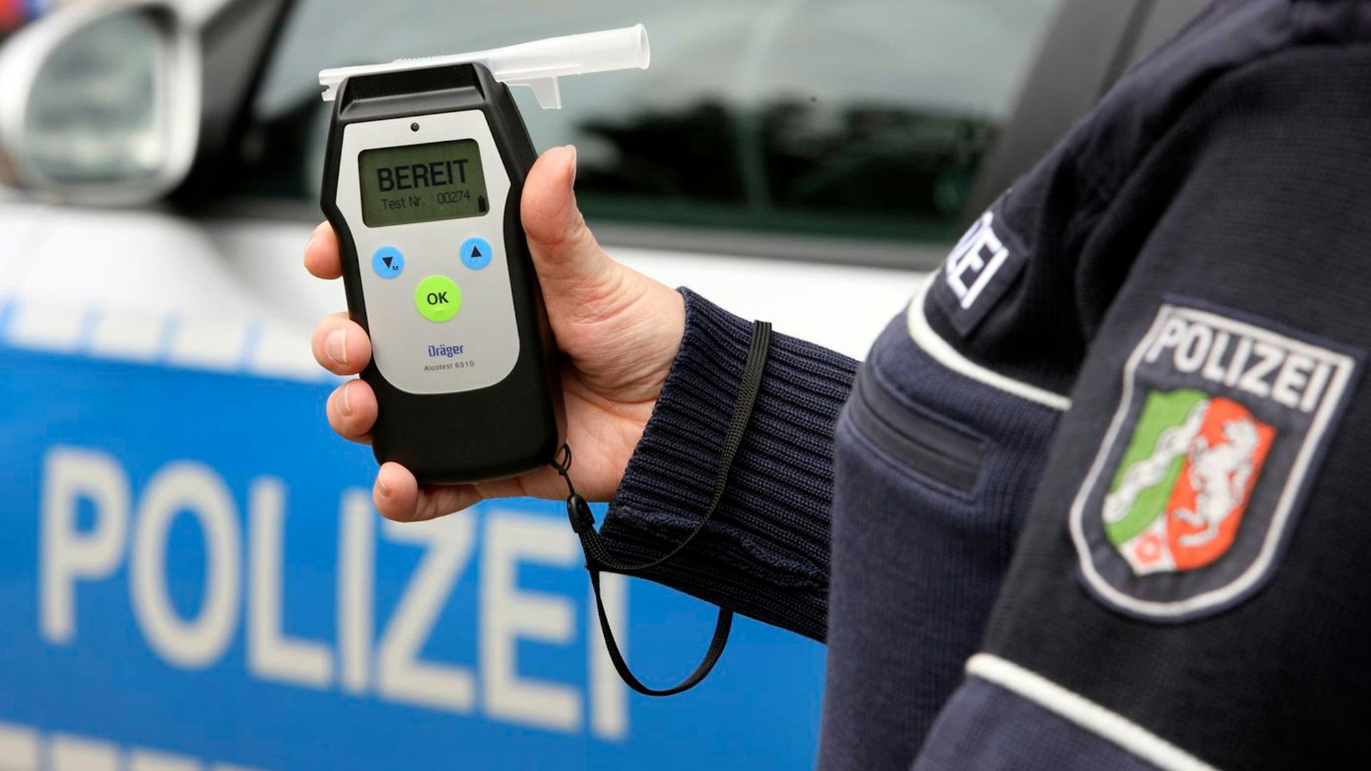 Das Bild ist ein Symbolfoto und zeigt einen Polizeibeamten mit einem Alkoholtestgerät.