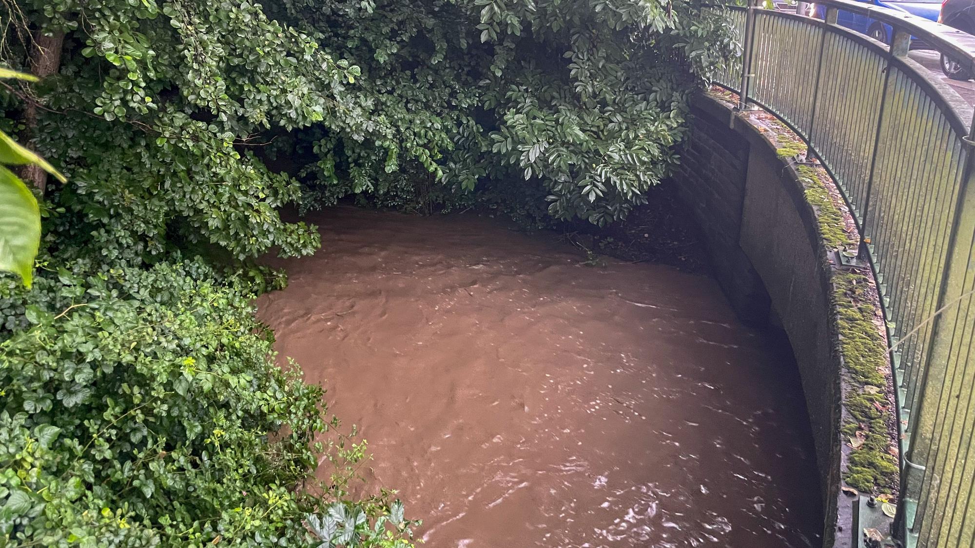 Das Wasser in einem Bach steht was zu einer Brücke.