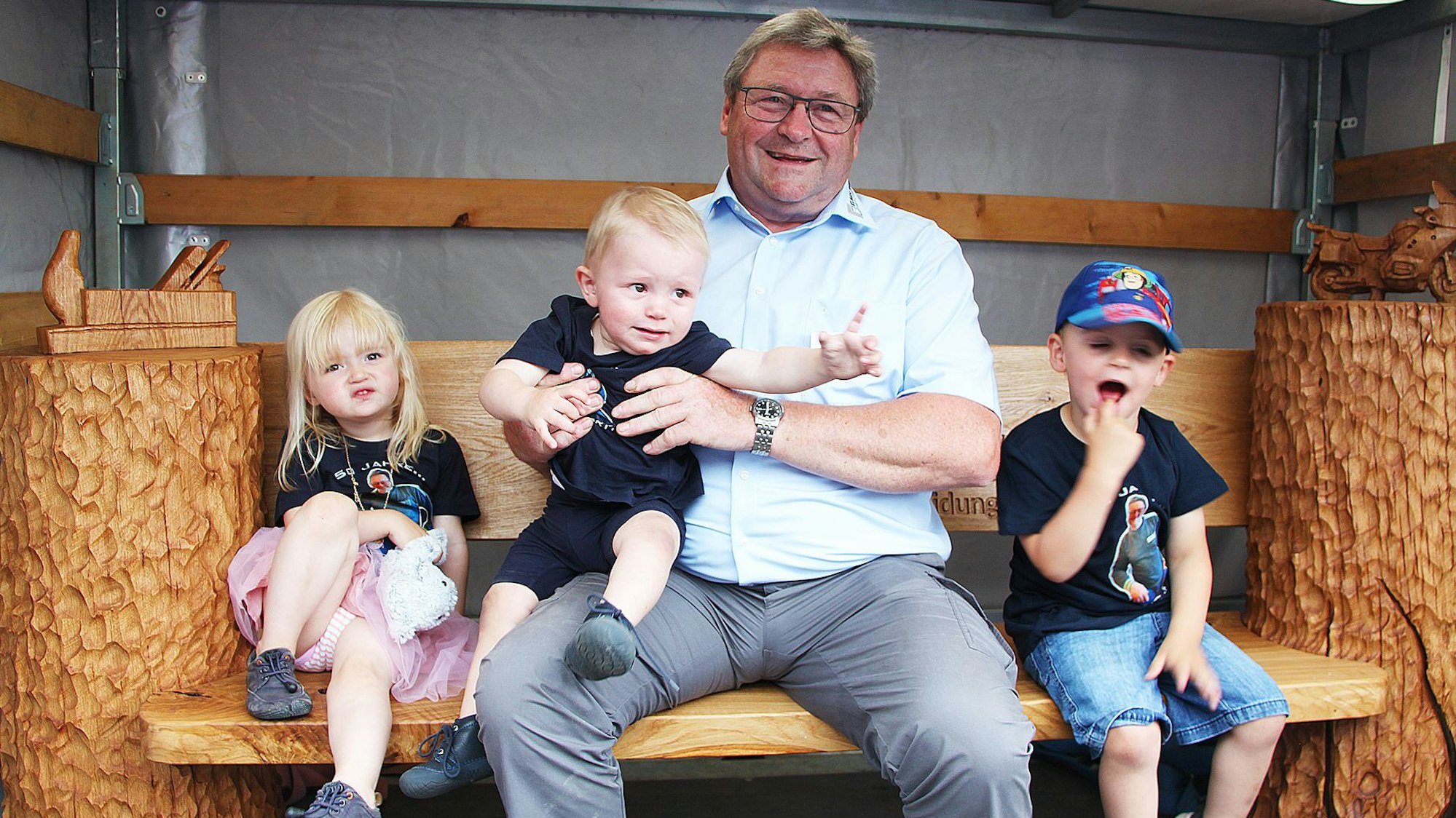 Axel Keul sitzt mit seinen drei Enkelkindern auf einer Bank.