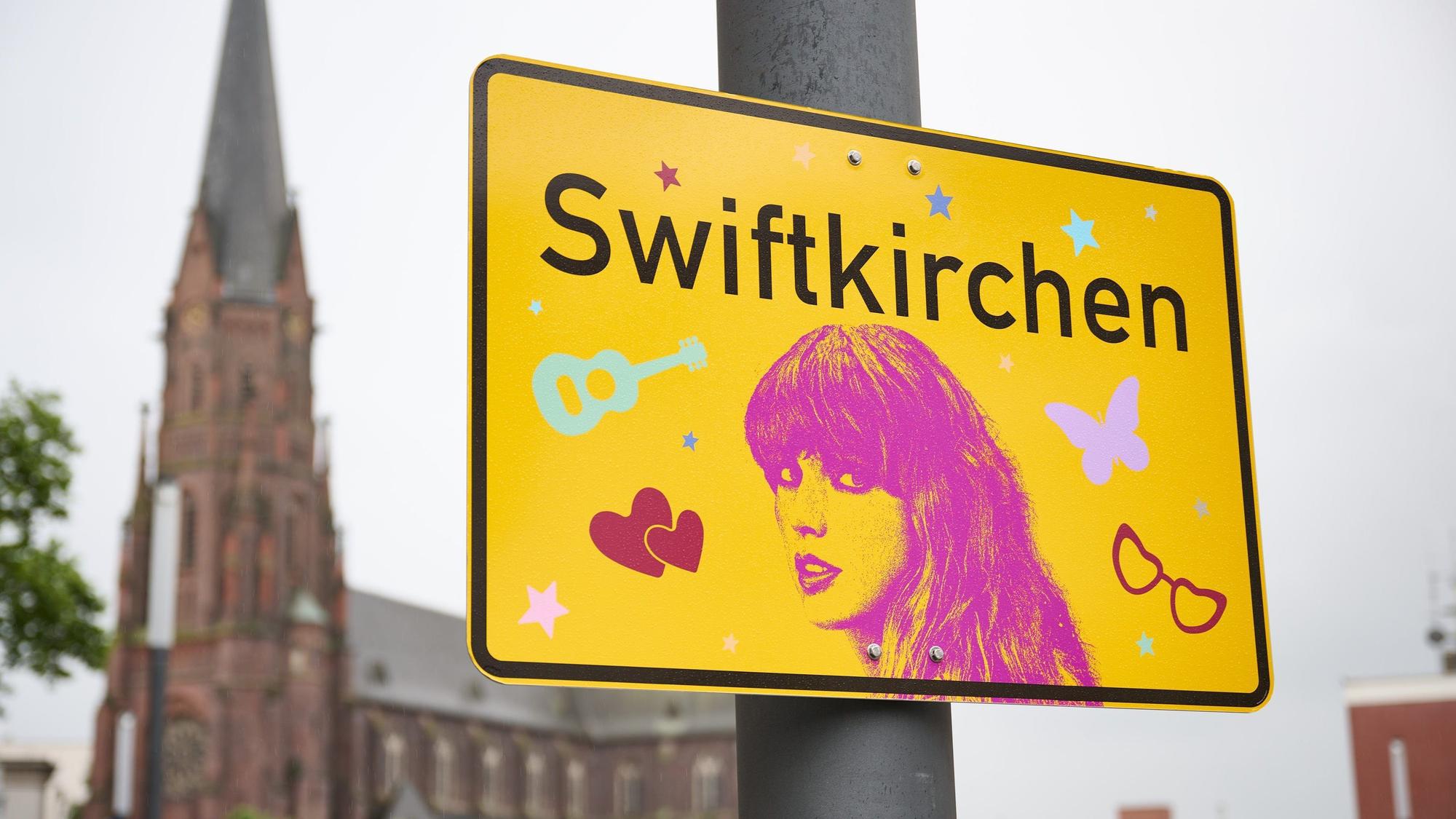 Das Ortsschild "Swiftkirchen" zu Ehren der Musikerin Taylor Swift hängt auf dem Heinrich-König-Platz, vor der Propsteikirche St. Augustinus.