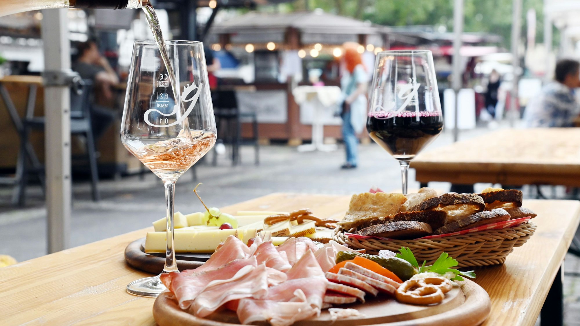 zwei Gläser Wein und Platten mit Schinken und Käse stehen auf einem Tisch