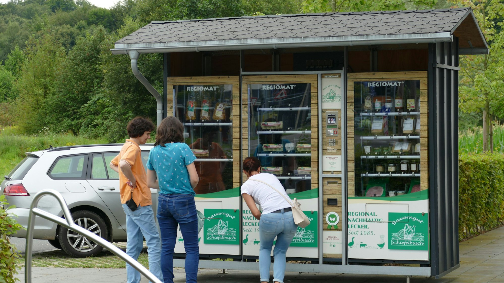 Menschen stehen vor einem Lebensmittelautomaten.