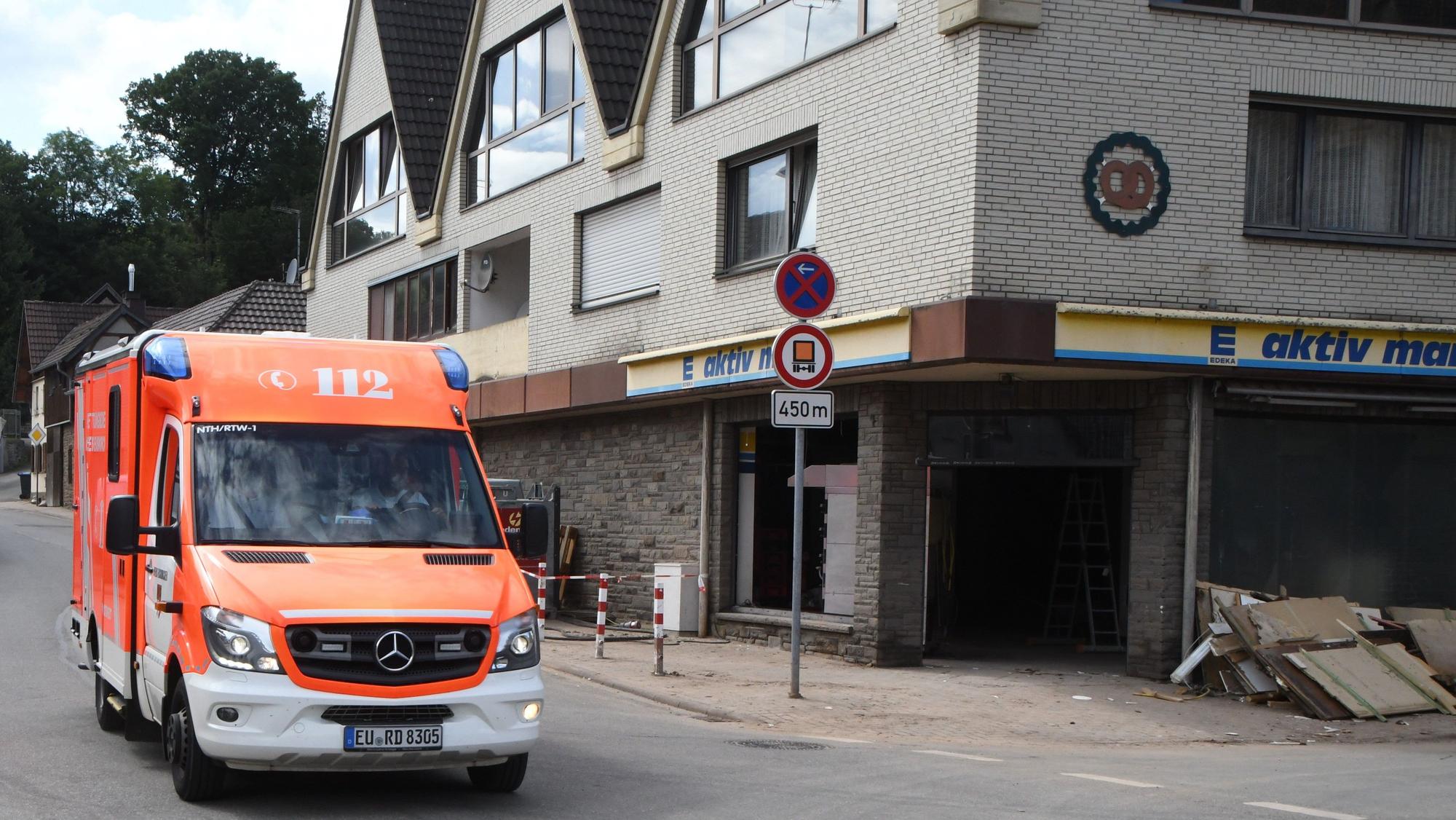 Schutt liegt vor dem kleinen Markt. Im Gebäude befand sich auch die Backstube. Ein Rettungswagen hält auf der Straße.