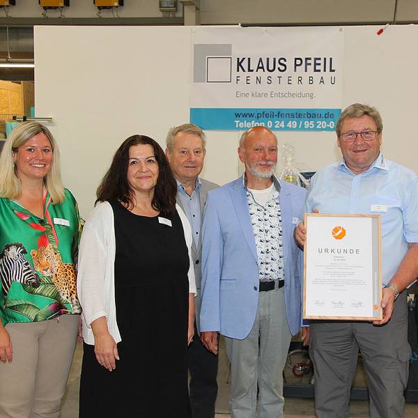 Axel Keul hält seine Urkunde in der Hand und ist von Gratulanten umgeben,