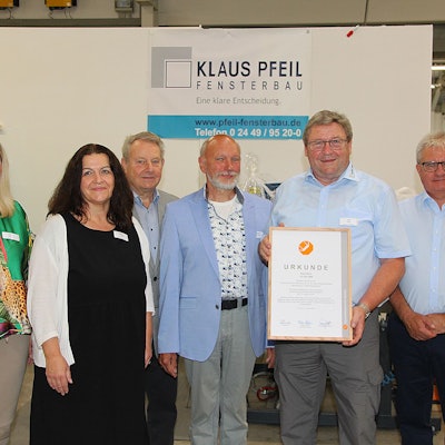 Axel Keul hält seine Urkunde in der Hand und ist von Gratulanten umgeben,