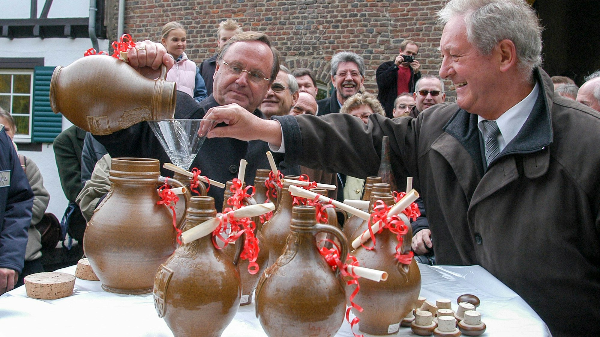 Zwei Männer füllen Wasser in Krüge.