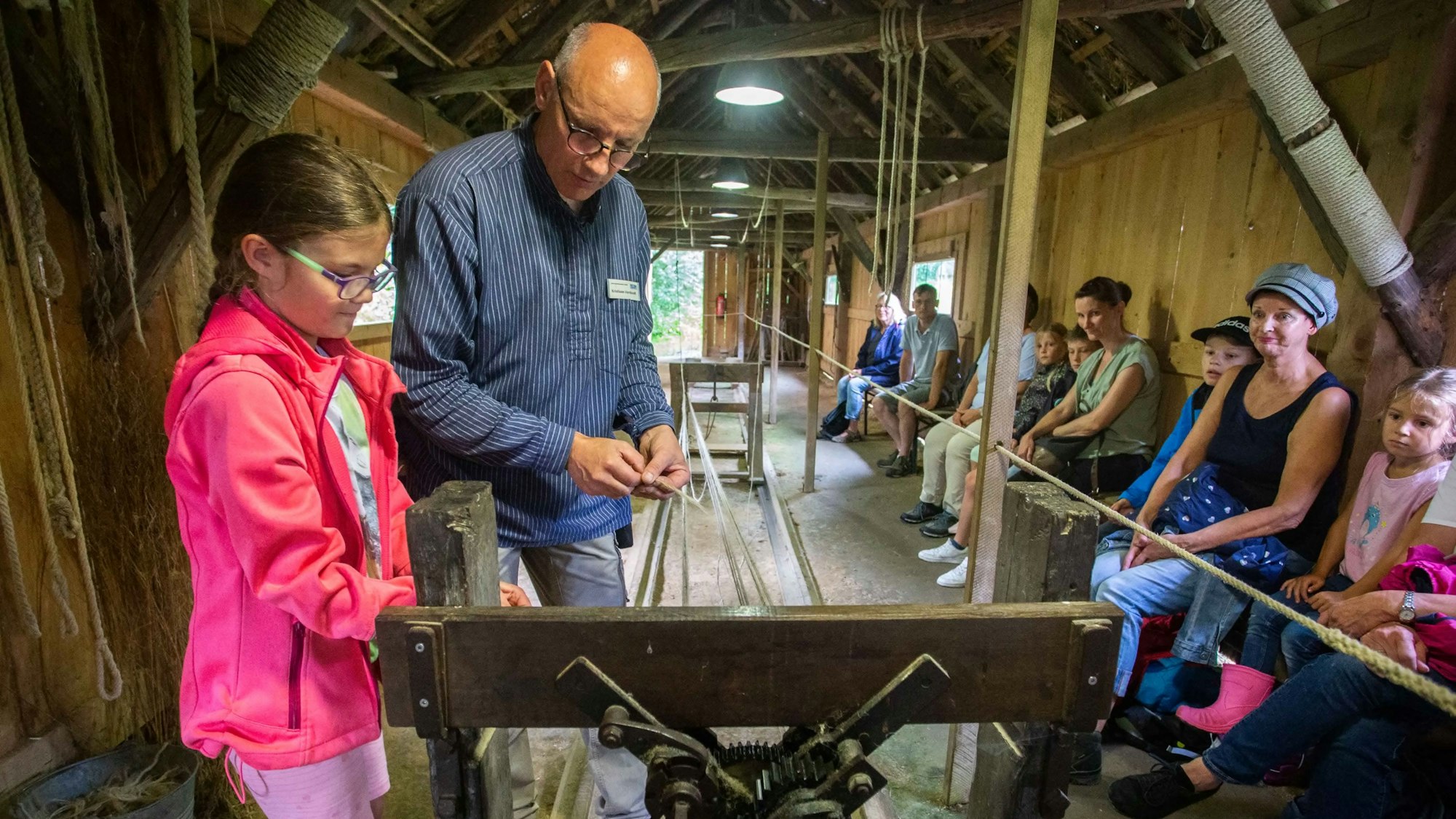 Ein achtjähriges Mädchen steht neben Museumsmitarbeiter Kristiaan Verdoodt und sieht zu, wie ein Seil entsteht.