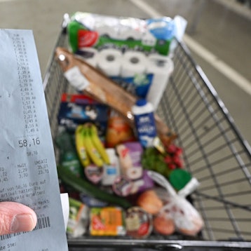 Ein Verbraucher hält nach einem Einkauf in einem Supermarkt einen Kassenzettel in der Hand.