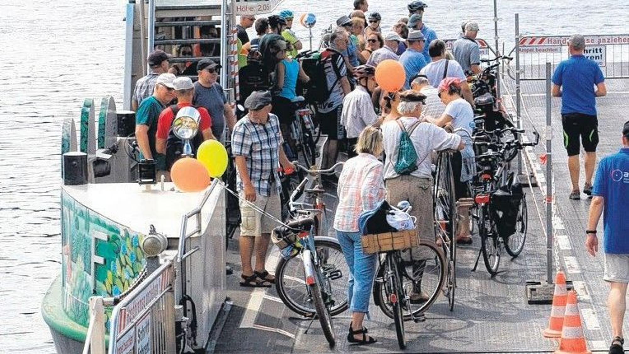 Fahrradfahrer stehen auf einer Fähre.