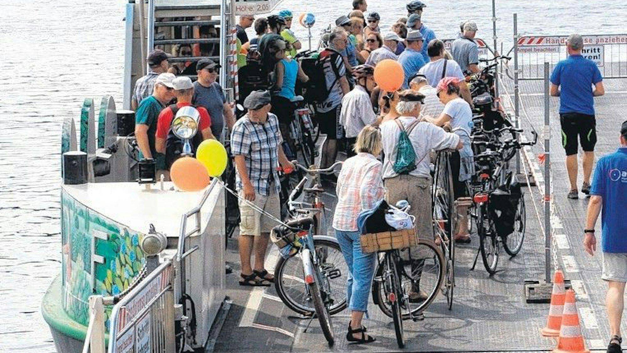 Fahrradfahrer stehen auf einer Fähre.