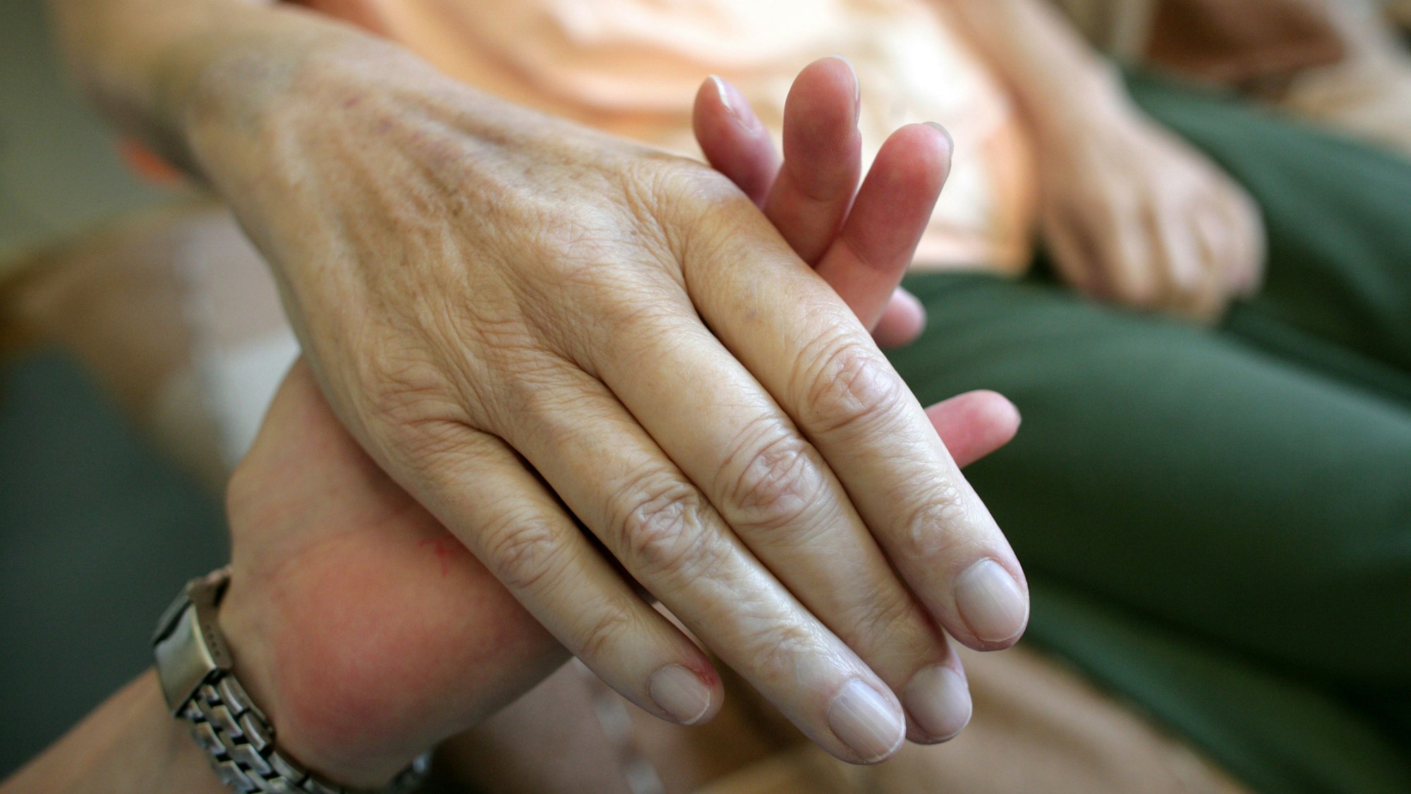 Eine Pflegerin hält die Hand einer kranken Frau.