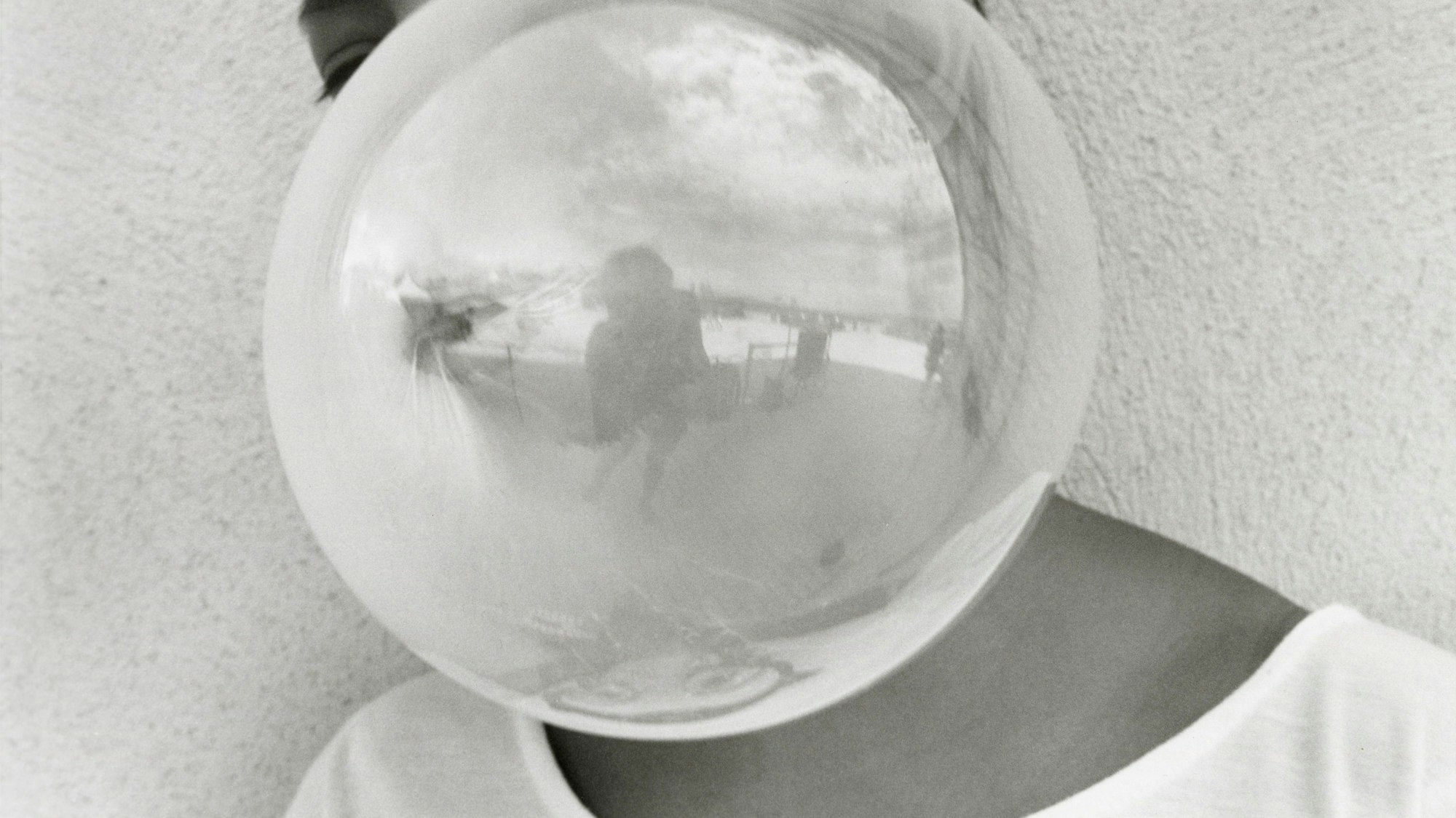 Eine Kaugummiblase verdeckt die Person dahinter. Dafür sieht man die gespiegelte Fotografin.