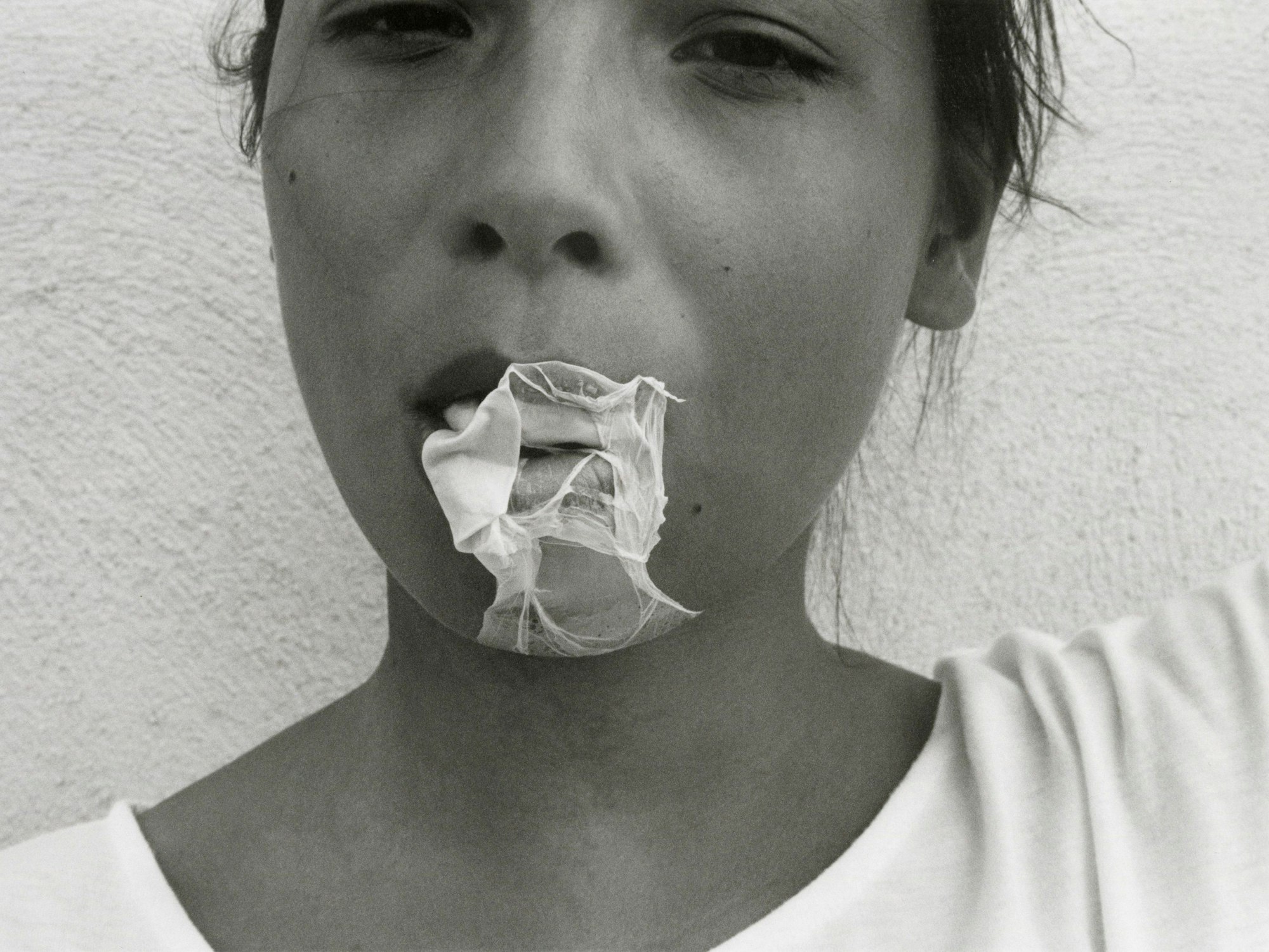 Eine junge Frau saugt eine geplatzte Kaugummiblase ein.