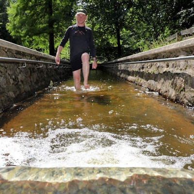 Ein Mann geht durch das Tretbecken der Wassertretstelle im Königsforst.