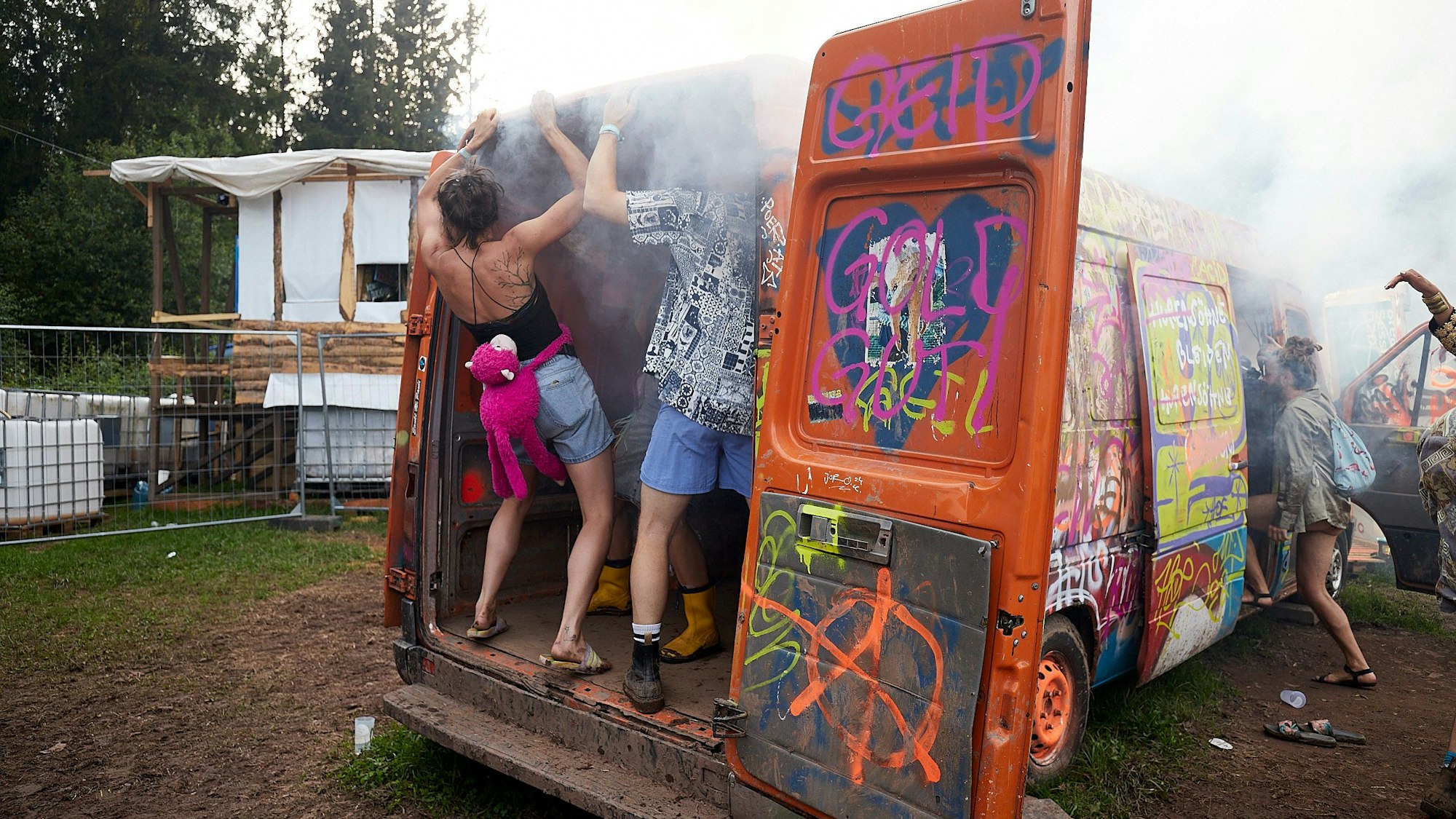 In einem bunt bemalten Transporter tanzen mehrere Festivalbesucher.