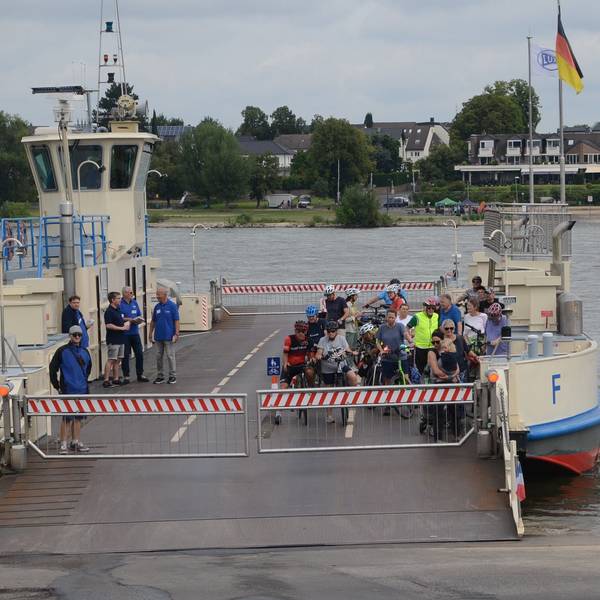 Eine Rheinfähre legt an. An Bord sind nur Radfahrer.