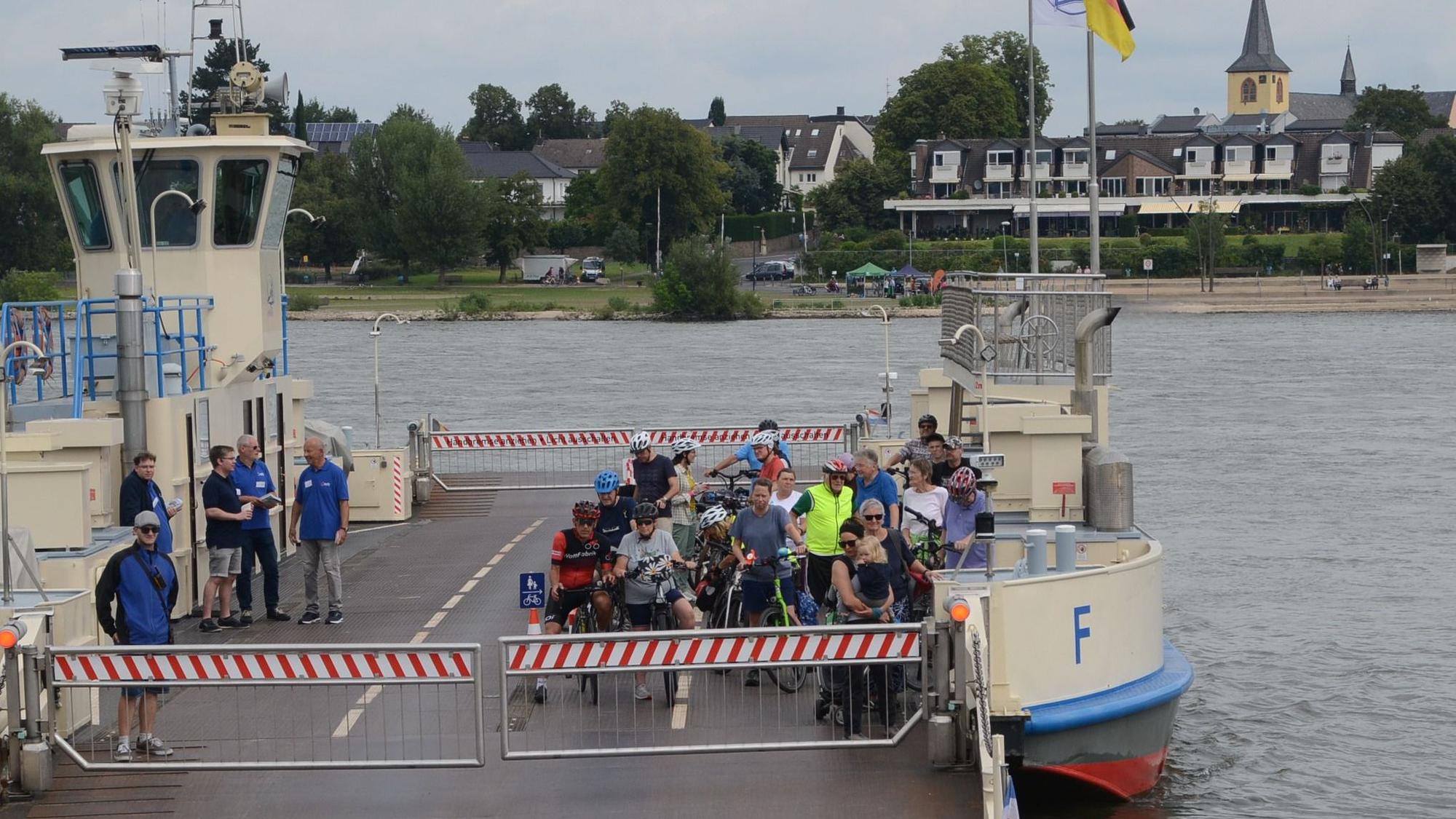 Eine Rheinfähre legt an. An Bord sind nur Radfahrer.