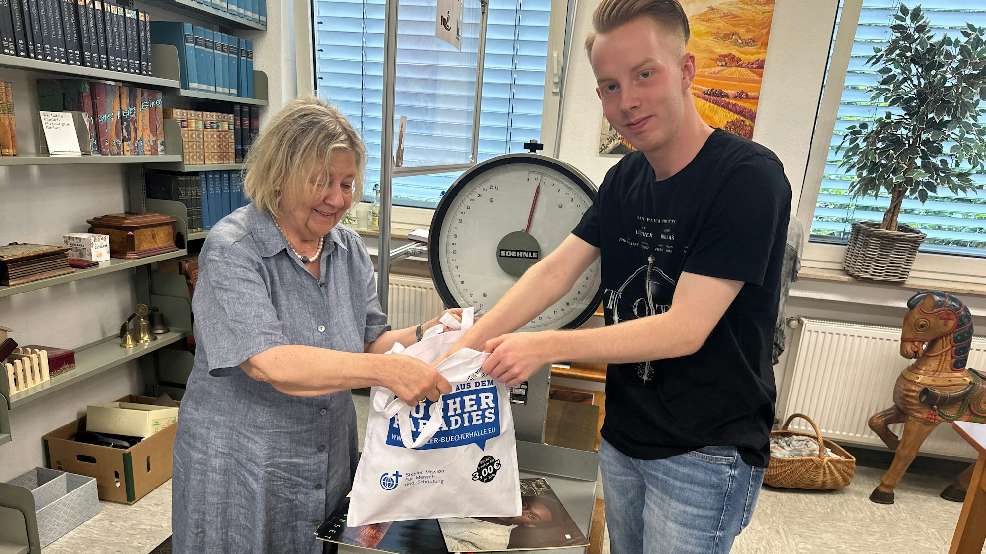 Gisela Lindner wiegt die Bücher, die Lehramtsstudent Jonathan Jungbluth gerade ausgesucht hat.