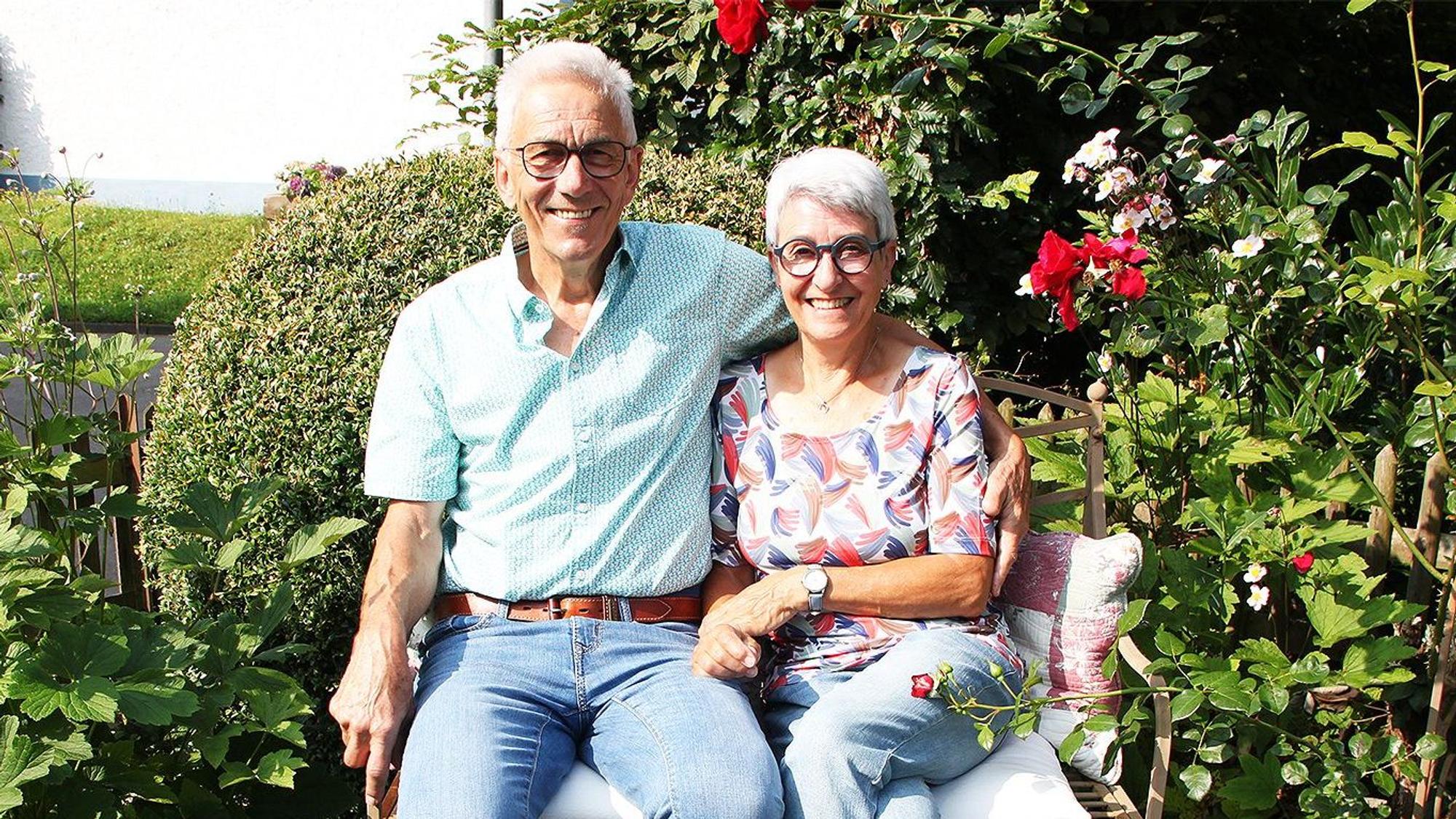 Jutta und Heinz-Anton Schneider sitzen nebeneinander auf einer Bank im Garten.