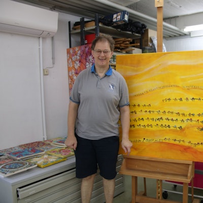 Ein junger Mann steht neben seinem Kunstwerk.