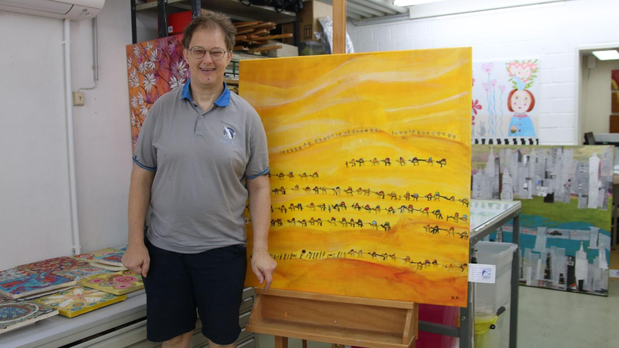 Ein junger Mann steht neben seinem Kunstwerk.
