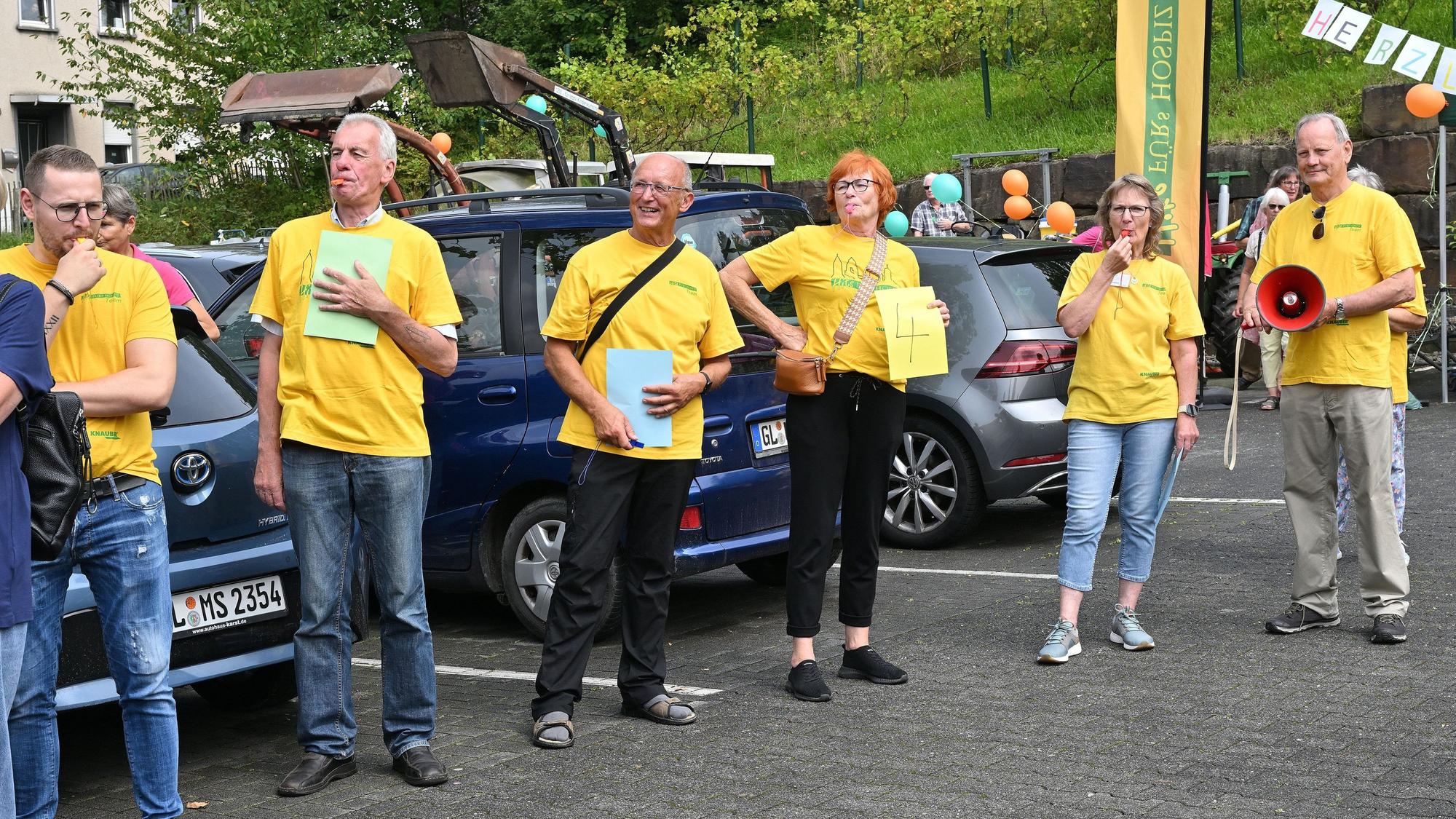 Menschen in gelben T-Shirts empfangen Heimkehrer auf einem Parkplatz.